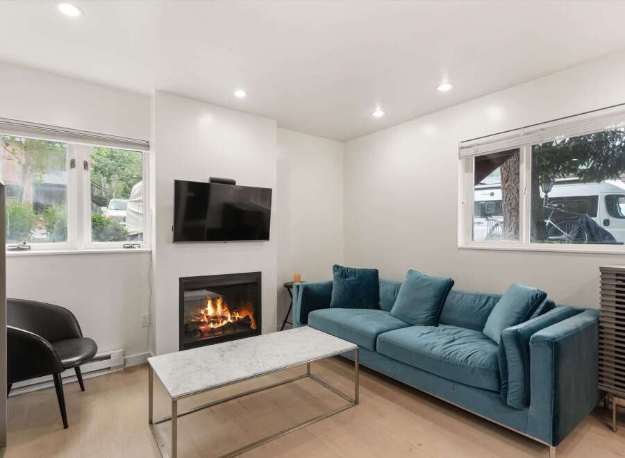 Cozy up by the fireplace in this inviting living room, featuring a plush teal sofa perfect for relaxation.