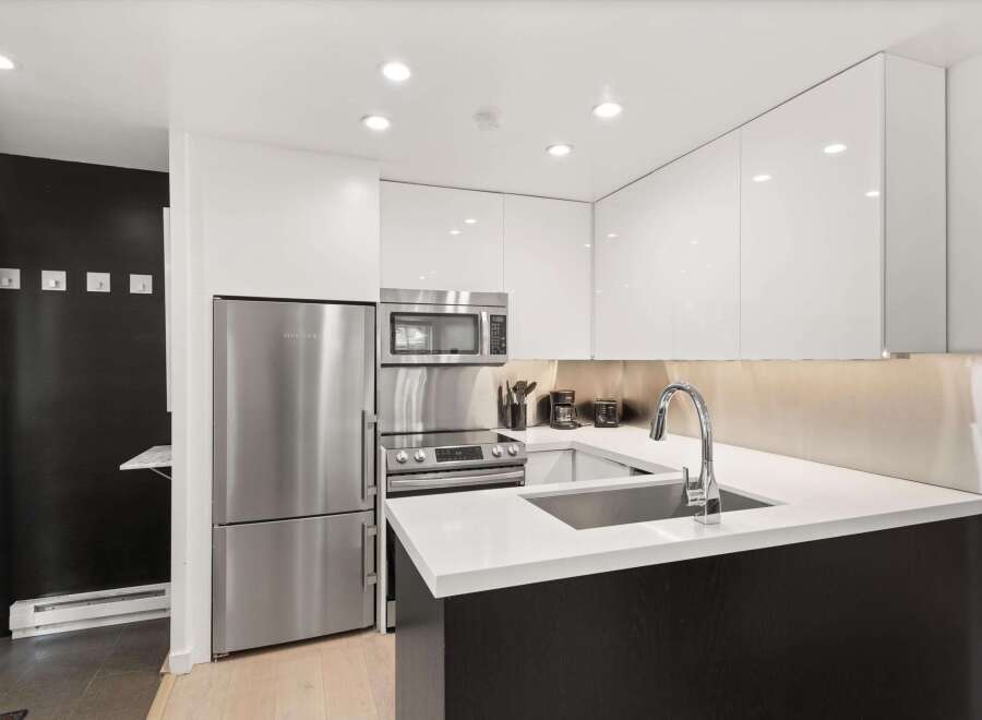 Experience modern living in this sleek kitchen featuring stainless steel appliances, including a refrigerator, microwave, and oven.