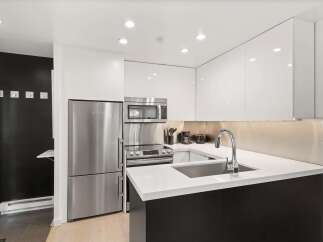 Experience modern living in this sleek kitchen featuring stainless steel appliances, including a refrigerator, microwave, and oven.