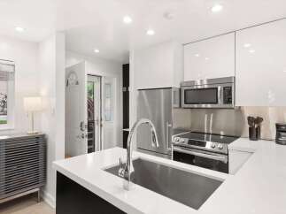 Experience modern living in this sleek kitchen featuring high-end stainless steel appliances, including a refrigerator, microwave, and a smooth-top range.