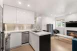 Experience modern living in this sleek kitchen featuring high-gloss white cabinetry and a stainless steel backsplash.