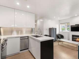Experience modern living in this sleek kitchen featuring high-gloss white cabinetry and a stainless steel backsplash.