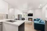 Experience modern living in this stylish open-concept space, featuring a sleek kitchen with a large sink and a cozy living area centered around a beautiful fireplace.