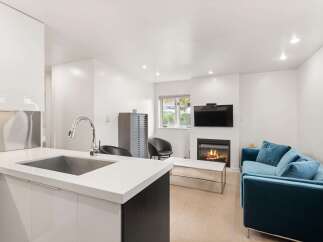 Experience modern living in this stylish open-concept space, featuring a sleek kitchen with a large sink and a cozy living area centered around a beautiful fireplace.