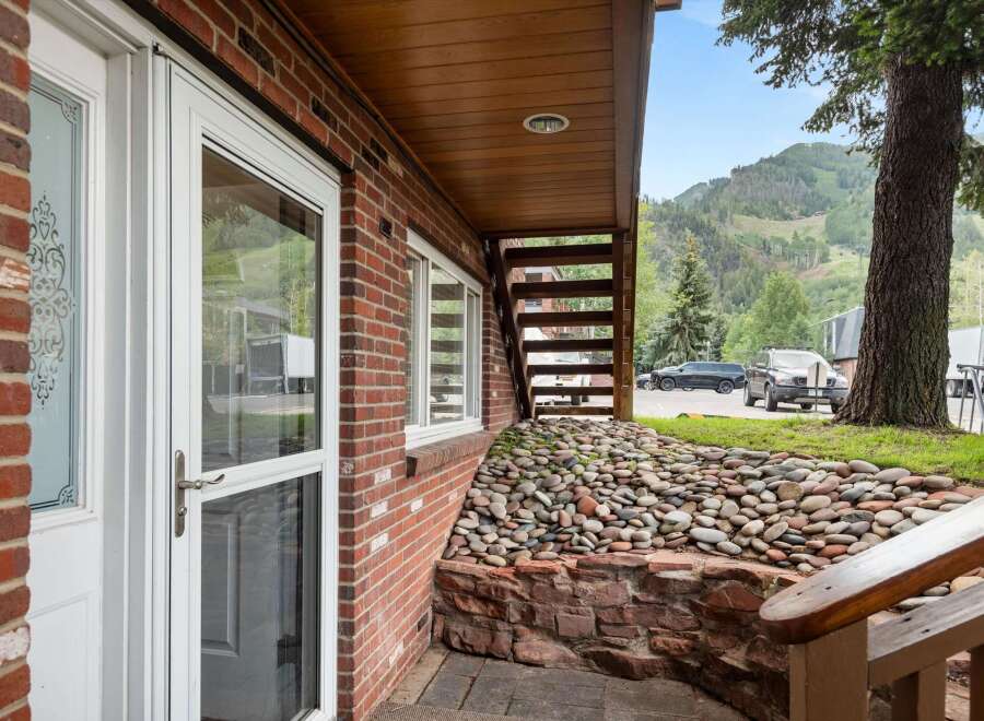 Experience mountain living with this charming brick home, featuring a welcoming entryway with decorative glass doors and large windows that offer scenic views.
