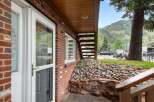 Experience mountain living with this charming brick home, featuring a welcoming entryway with decorative glass doors and large windows that offer scenic views.