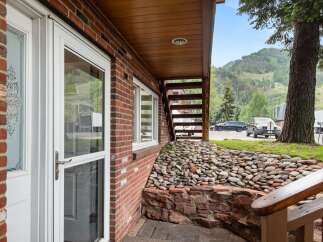 Experience mountain living with this charming brick home, featuring a welcoming entryway with decorative glass doors and large windows that offer scenic views.