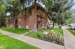 Charming brick and wood-sided apartment building nestled amongst mature trees.