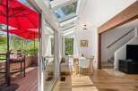 Enjoy indoor-outdoor living in this sun-drenched sunroom featuring a retractable glass roof and access to a private deck with red umbrellas.