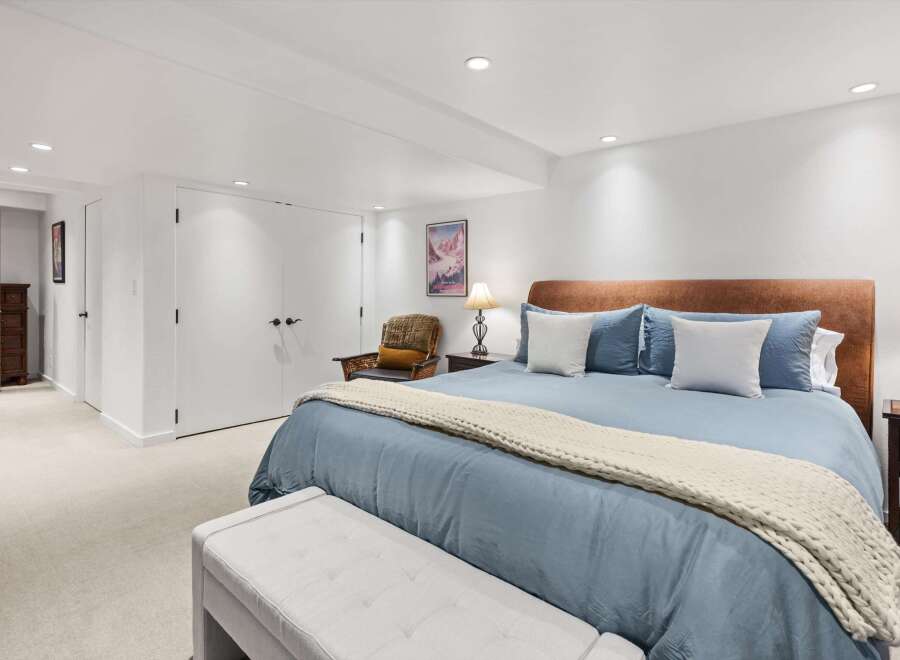 This spacious bedroom features a comfortable king-size bed with a plush blue comforter and a cozy knit throw.