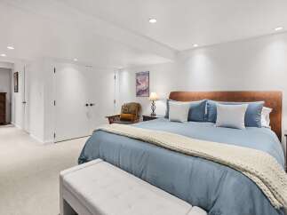 This spacious bedroom features a comfortable king-size bed with a plush blue comforter and a cozy knit throw.