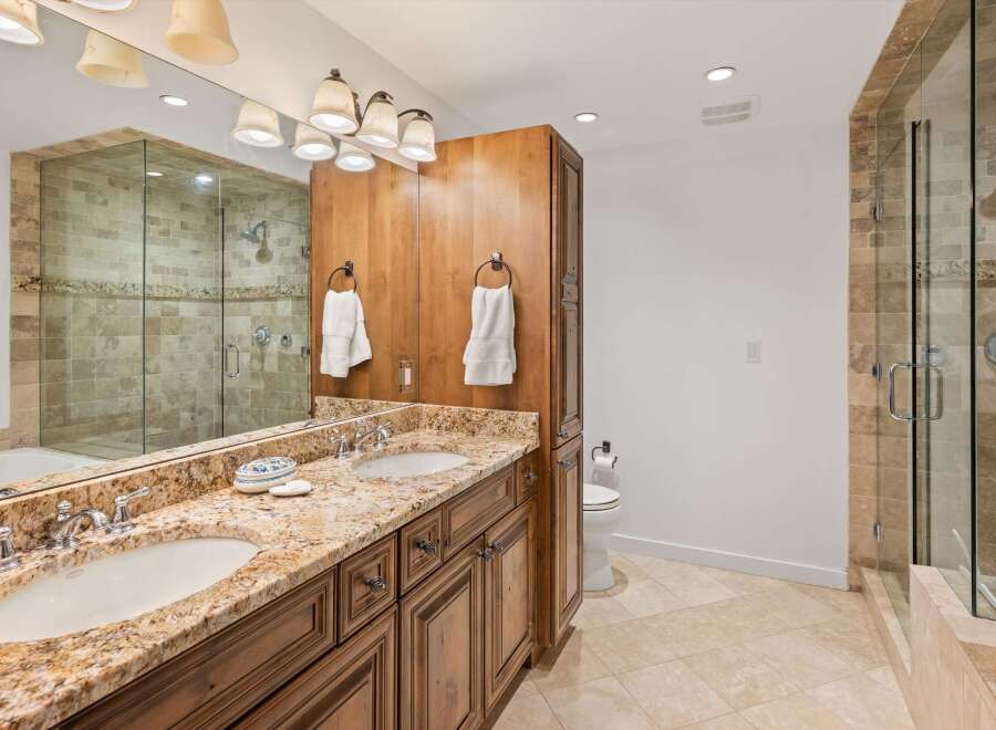 Experience luxury in this stunning bathroom featuring a spacious double vanity with granite countertops and ample storage.