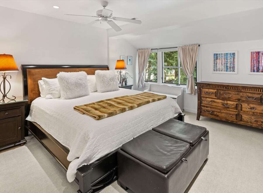 Experience ultimate comfort in this luxurious master bedroom, featuring a king-size bed adorned with plush white pillows and a stylish faux fur throw.