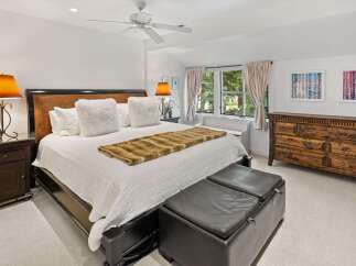 Experience ultimate comfort in this luxurious master bedroom, featuring a king-size bed adorned with plush white pillows and a stylish faux fur throw.