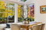 Enjoy breathtaking autumn views from this dining area, featuring large windows that showcase vibrant fall foliage and distant mountains.