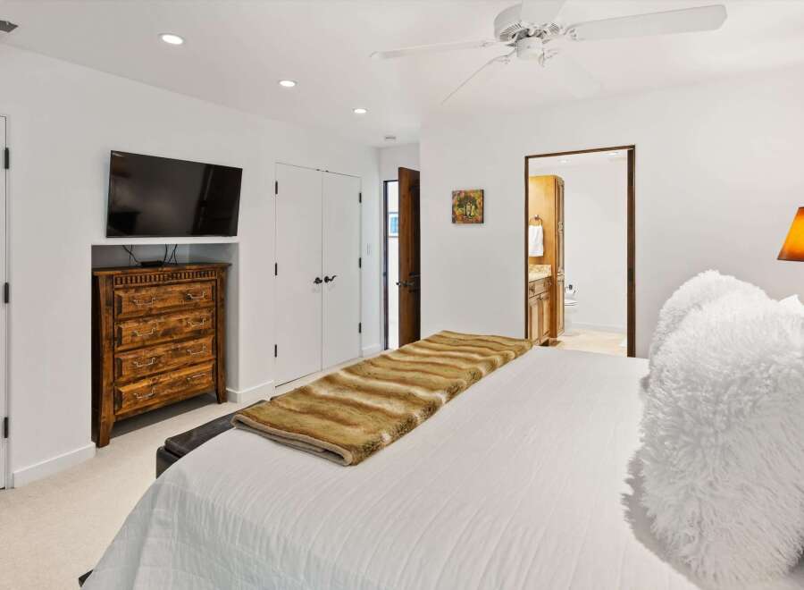 This master bedroom offers a luxurious retreat with a plush white duvet and a striking faux fur throw.