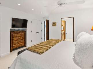 This master bedroom offers a luxurious retreat with a plush white duvet and a striking faux fur throw.