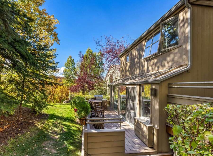 Enjoy the vibrant autumn colors surrounding this beautiful home, featuring a spacious deck perfect for outdoor entertaining.