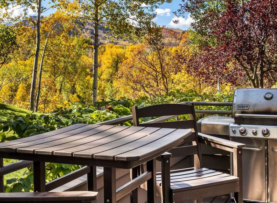 Enjoy the vibrant autumn foliage from this stunning deck, complete with a Weber grill and outdoor dining set.
