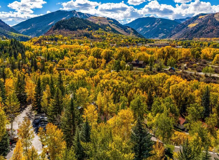 Experience the breathtaking beauty of autumn in this stunning mountain landscape, showcasing vibrant fall foliage against a backdrop of majestic peaks.