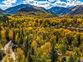 Experience the breathtaking beauty of autumn in this stunning mountain landscape, showcasing vibrant fall foliage against a backdrop of majestic peaks.