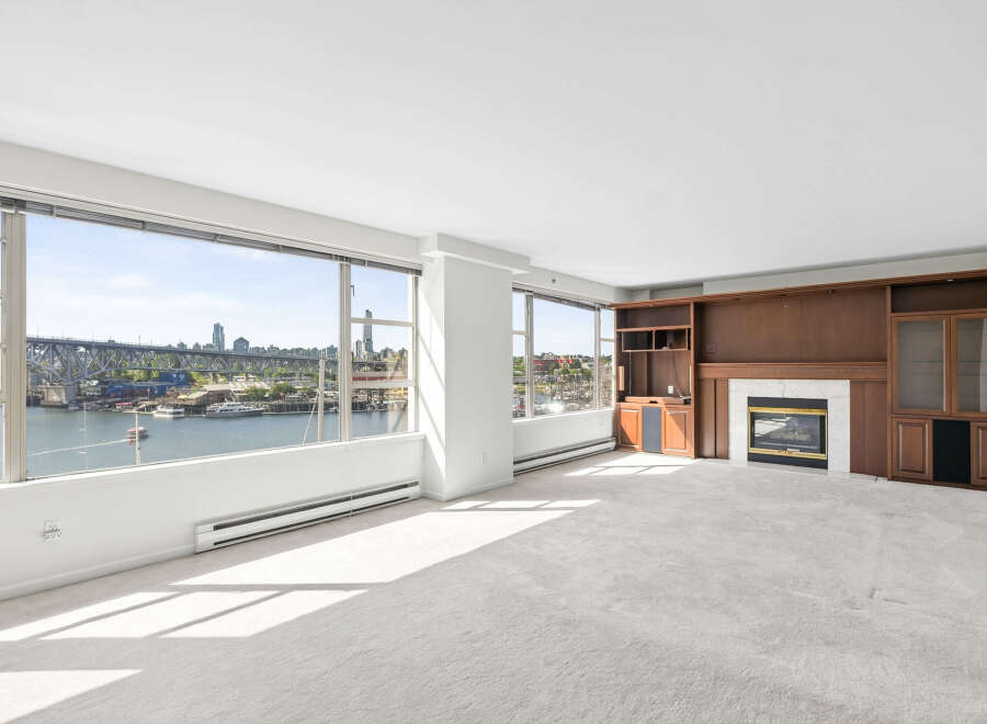 Experience breathtaking waterfront views from this spacious living room, featuring expansive windows that showcase the city skyline and a picturesque harbor.