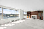 Experience breathtaking waterfront views from this spacious living room, featuring expansive windows that showcase the city skyline and a picturesque harbor.