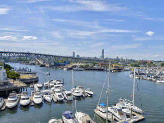Experience waterfront living at its finest with this stunning property offering panoramic views of a bustling marina and a picturesque city skyline.
