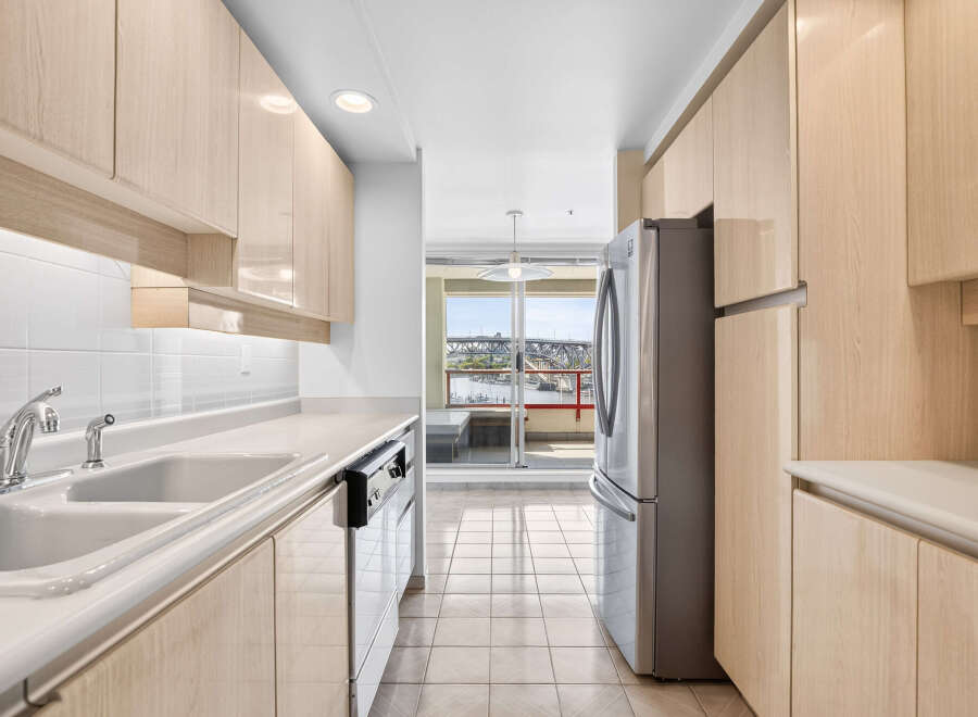 Discover this bright and airy kitchen featuring sleek, light wood cabinetry and a double basin sink with a modern faucet.
