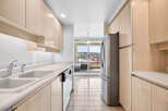 Discover this bright and airy kitchen featuring sleek, light wood cabinetry and a double basin sink with a modern faucet.