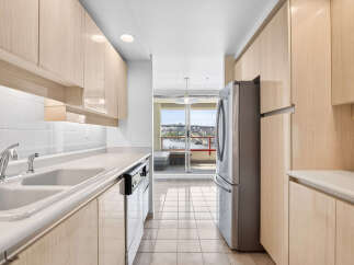 Discover this bright and airy kitchen featuring sleek, light wood cabinetry and a double basin sink with a modern faucet.