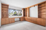 This spacious room features custom-built wooden cabinetry and shelving, offering ample storage and display space.