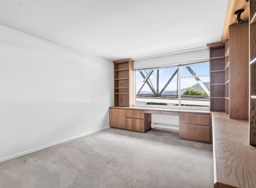 This spacious room features custom built-in wooden cabinetry and shelving, perfect for a home office or library.