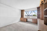 This spacious room features custom built-in wooden cabinetry and shelving, perfect for a home office or library.