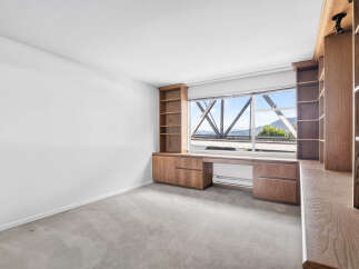 This spacious room features custom built-in wooden cabinetry and shelving, perfect for a home office or library.