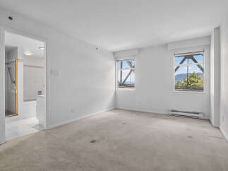 Discover this spacious bedroom featuring a neutral carpet and large windows that offer stunning views of the surrounding landscape and bridge structure.