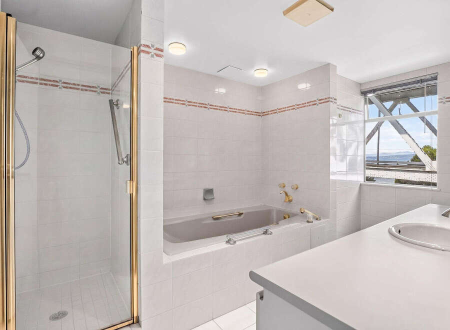 Experience luxury and comfort in this stunning bathroom, featuring a spacious walk-in shower with elegant gold trim and a deep soaking bathtub perfect for relaxation.