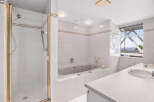 Experience luxury and comfort in this stunning bathroom, featuring a spacious walk-in shower with elegant gold trim and a deep soaking bathtub perfect for relaxation.