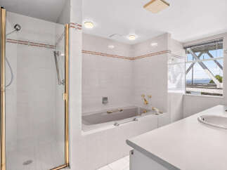 Experience luxury and comfort in this stunning bathroom, featuring a spacious walk-in shower with elegant gold trim and a deep soaking bathtub perfect for relaxation.