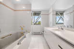 This spacious bathroom features a luxurious bathtub with gold-toned fixtures and a sleek vanity with a double sink.