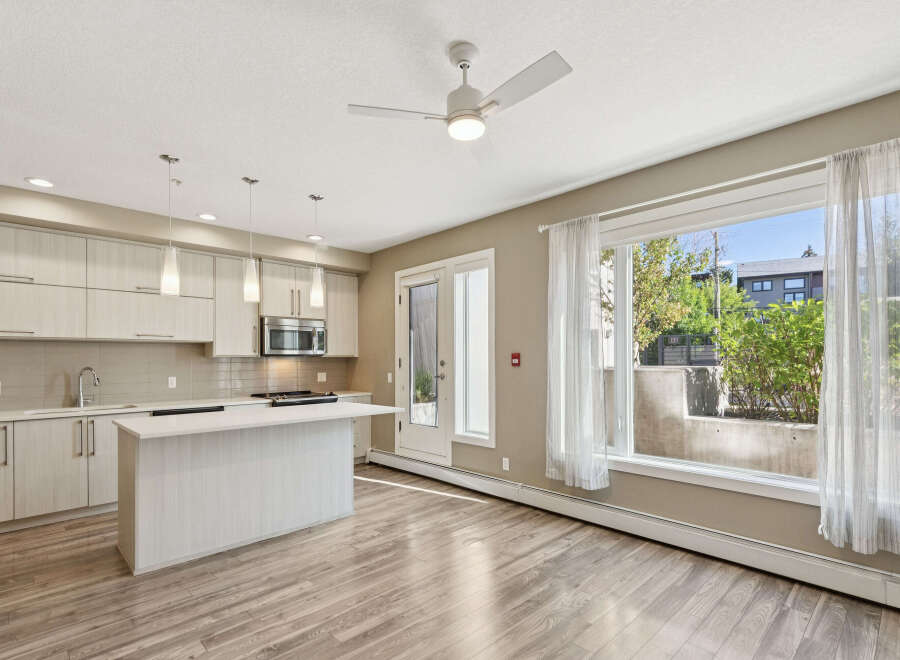 Experience modern living in this bright and airy condo featuring a sleek kitchen with ample cabinet space and a central island perfect for entertaining.
