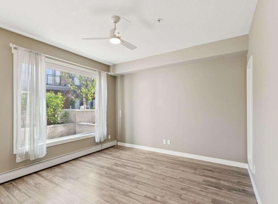 Bright and airy living space featuring a large window with sheer curtains, allowing natural light to flood the room.