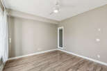 Experience modern living in this spacious room featuring a sleek ceiling fan and elegant wood-look flooring.