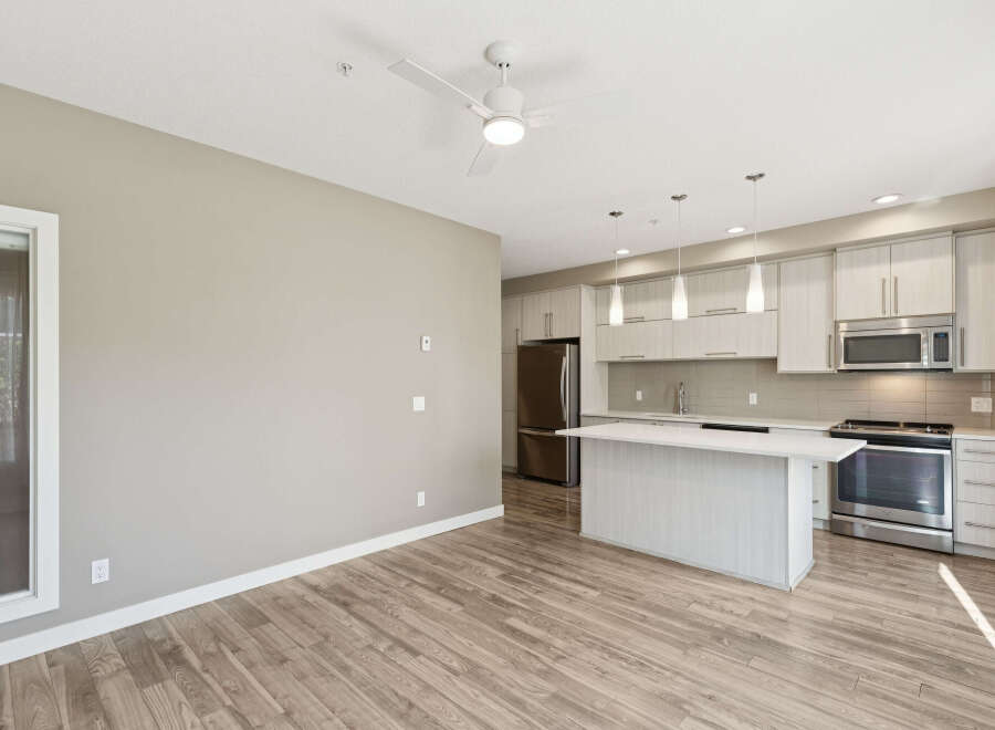 Experience modern living in this bright and airy open-concept space, featuring a sleek kitchen with stainless steel appliances and a convenient island.