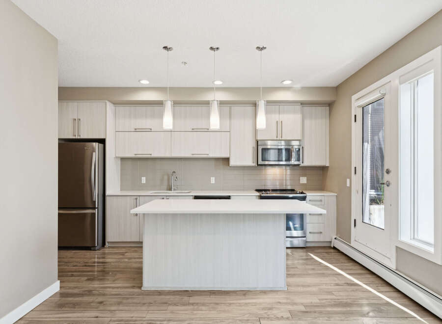 Discover this modern kitchen featuring sleek, light wood cabinetry and a spacious island with a quartz countertop.
