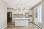Discover this modern kitchen featuring sleek, light wood cabinetry and a spacious island with a quartz countertop.