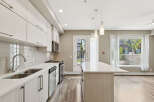 Experience modern living in this stunning kitchen featuring sleek white cabinetry, a spacious quartz island, and a complementary tiled backsplash.