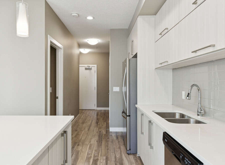 Step into a modern kitchen featuring sleek white cabinetry and a gleaming stainless steel refrigerator.
