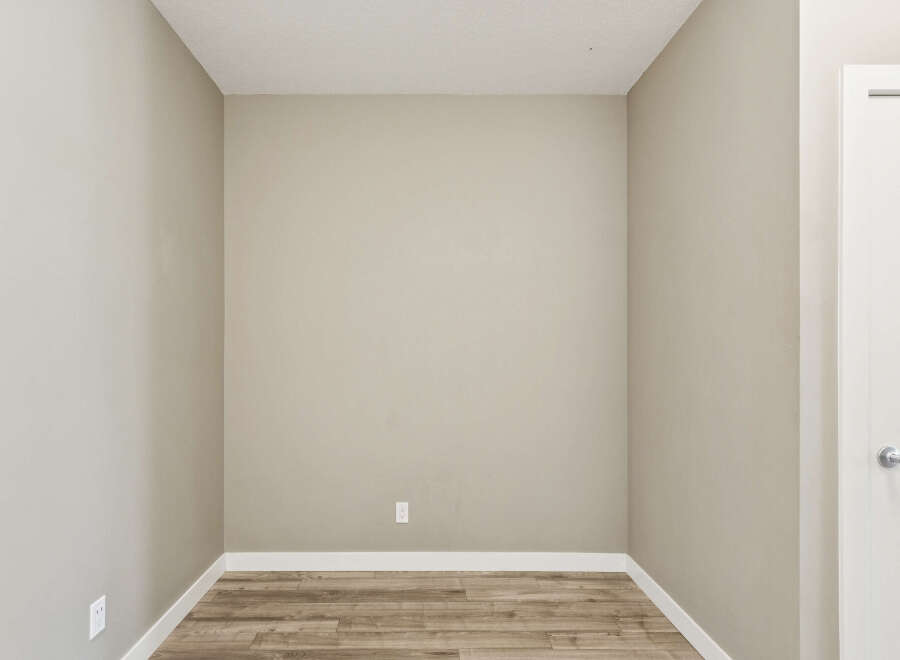 This image showcases an empty room with neutral-toned walls and a light wood-look floor, creating a blank canvas for potential buyers.