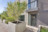 Experience modern urban living with this stunning property featuring sleek corrugated metal siding and a private balcony overlooking lush greenery.